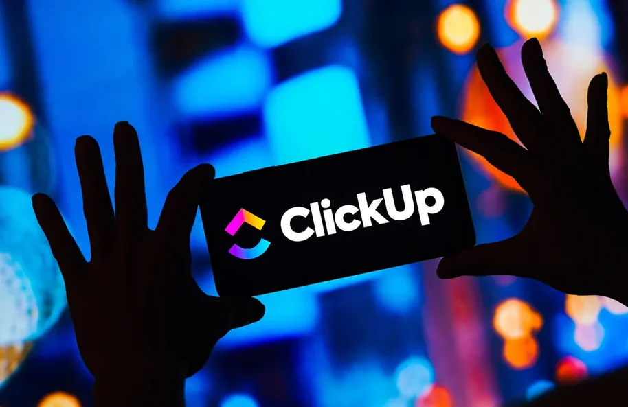 Logotipo do ClickUp em painel iluminado com mãos em silhueta