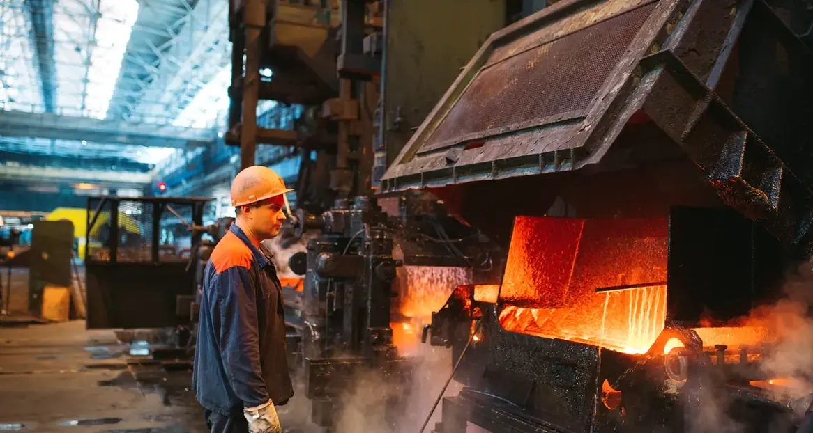 Operadores de capacete diante de forno em siderúrgica